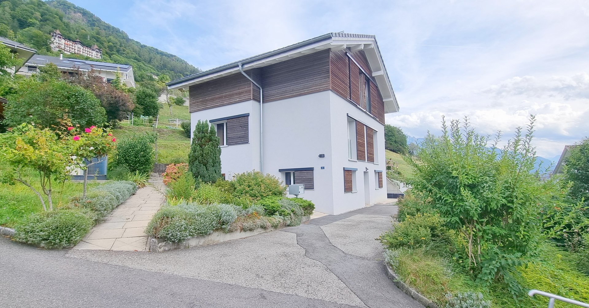 Maison blanche et brune, allée et jardin autour